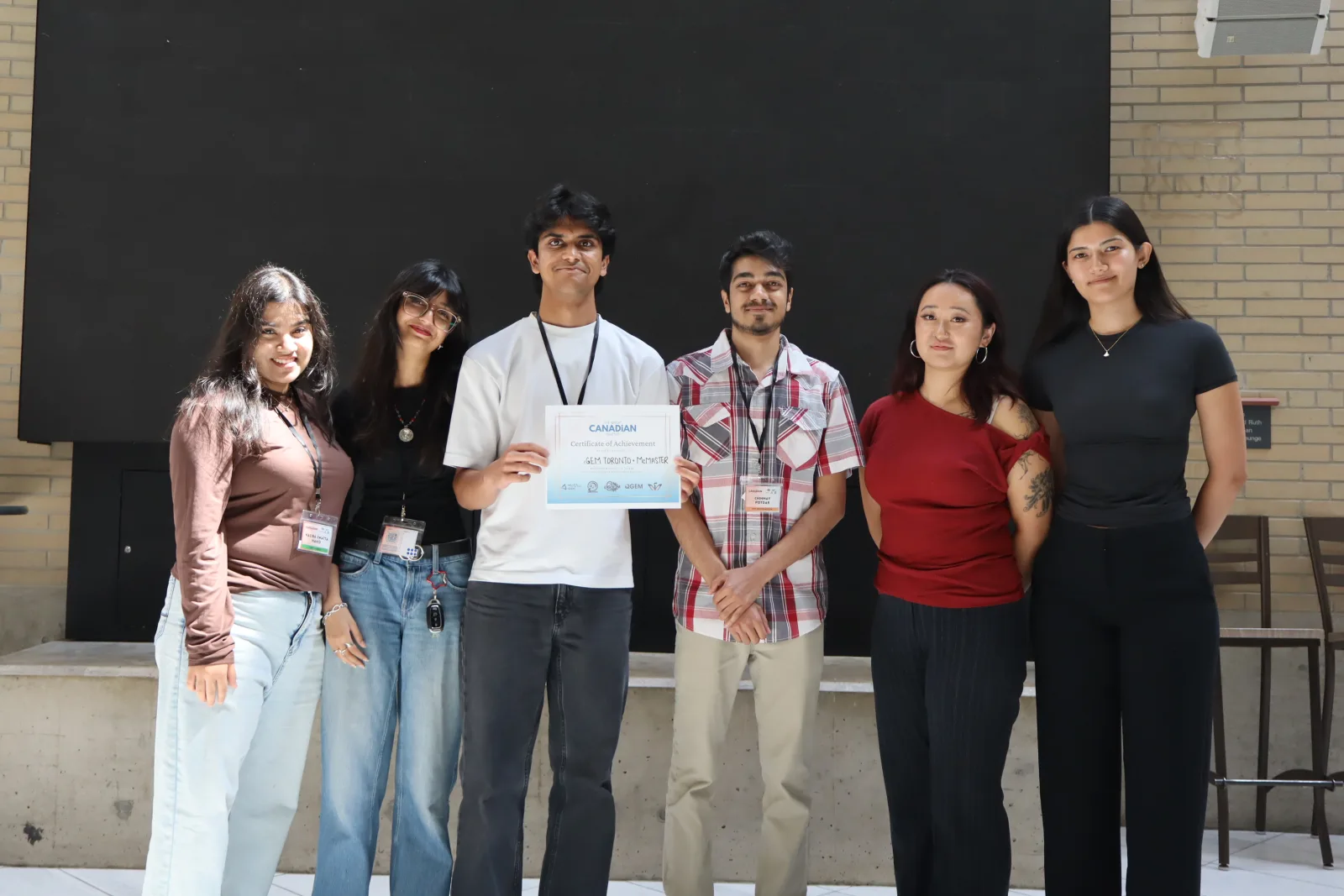 Team poses outdoors with its Great Canadian Meetup award, McMaster University, 8–9 August 2026