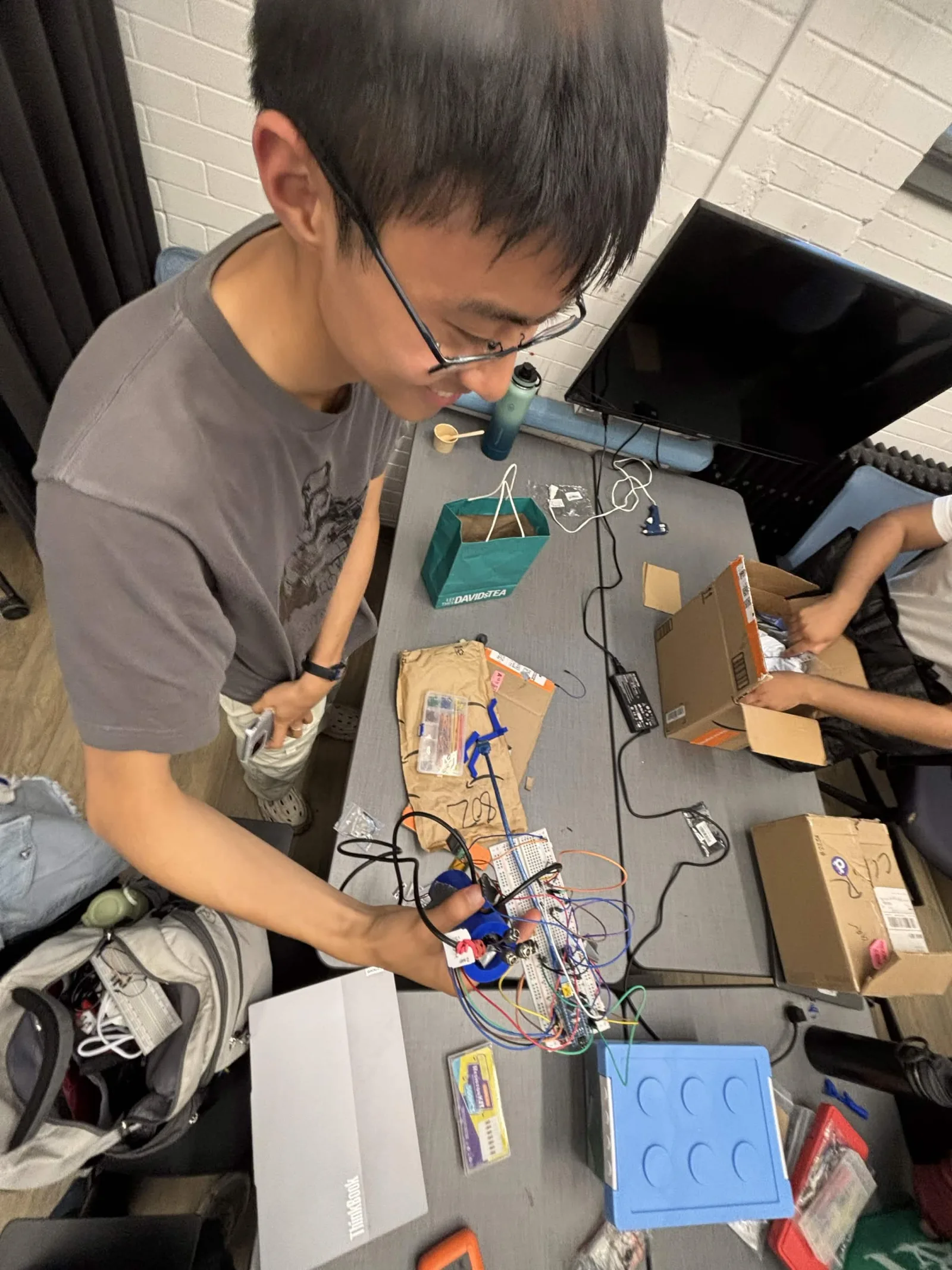 Hardware team unpacking new components and wiring a bioreactor subsystem, late July 2026