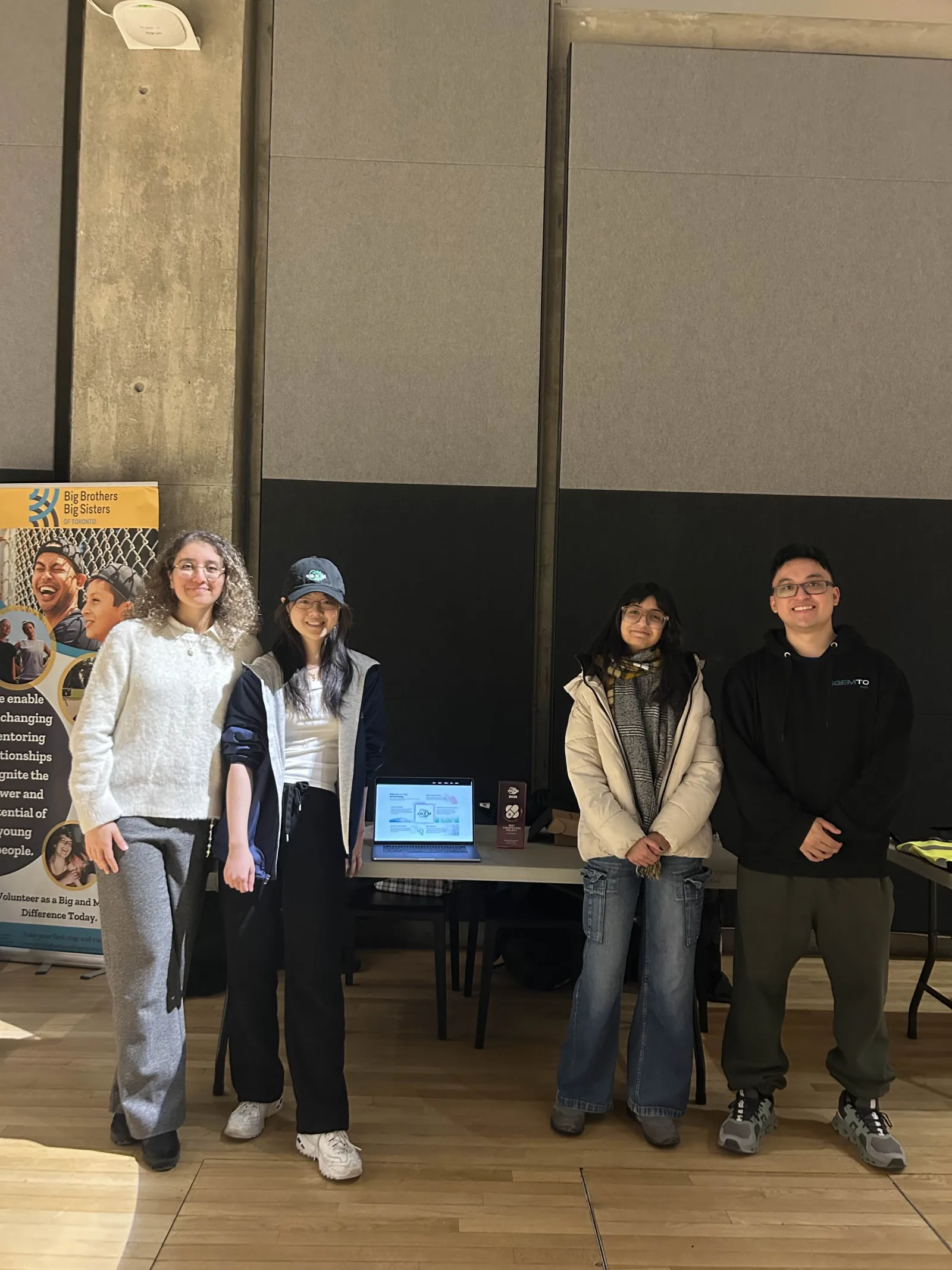 Team members pose together at their community fair booth, February 2026
