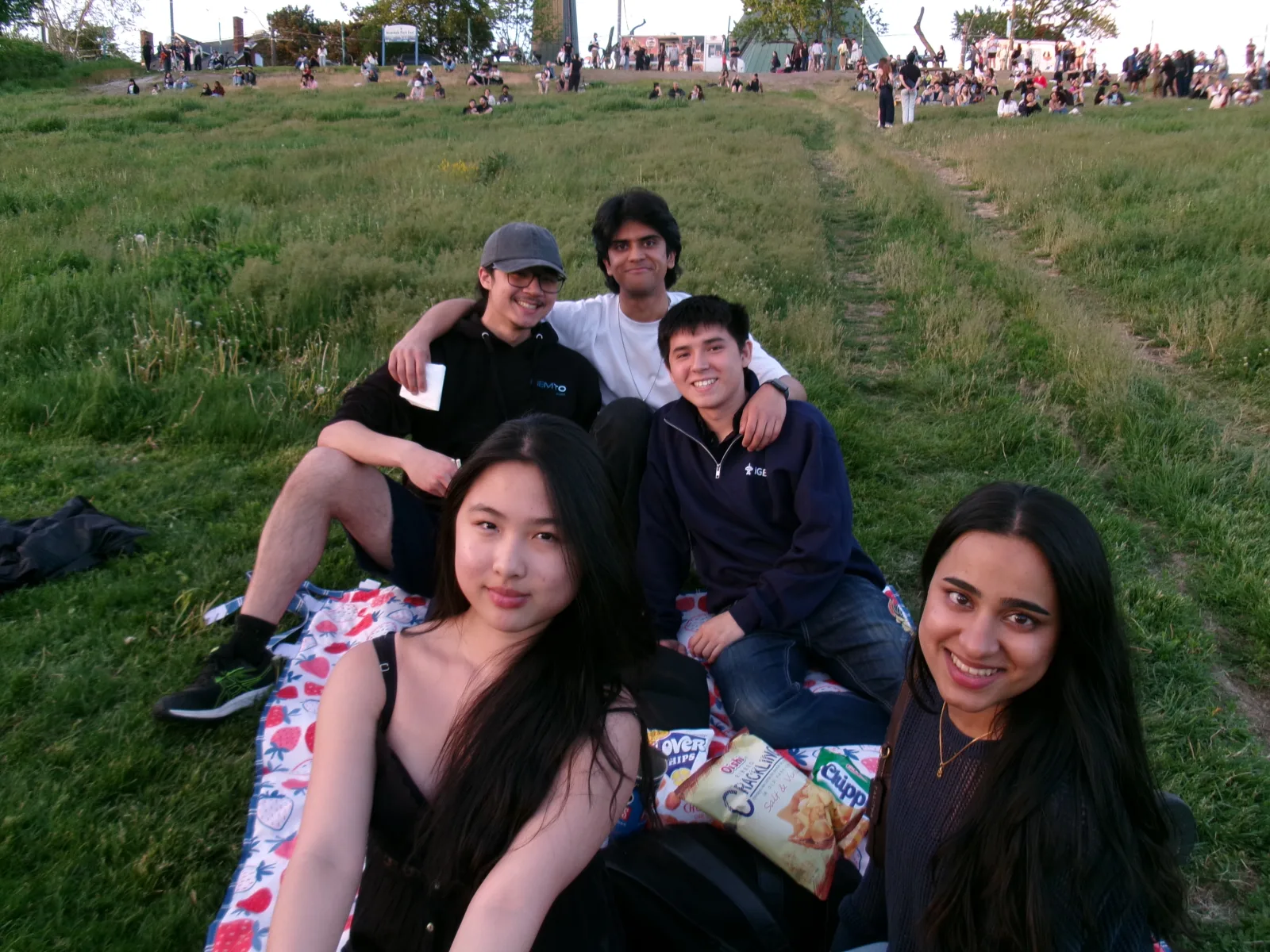 Team members share a picnic blanket during an evening park outing