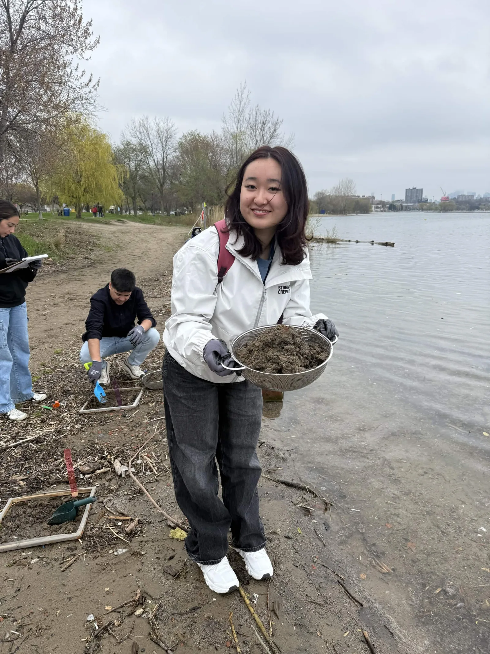 Showing off a sieve of collected shoreline debris