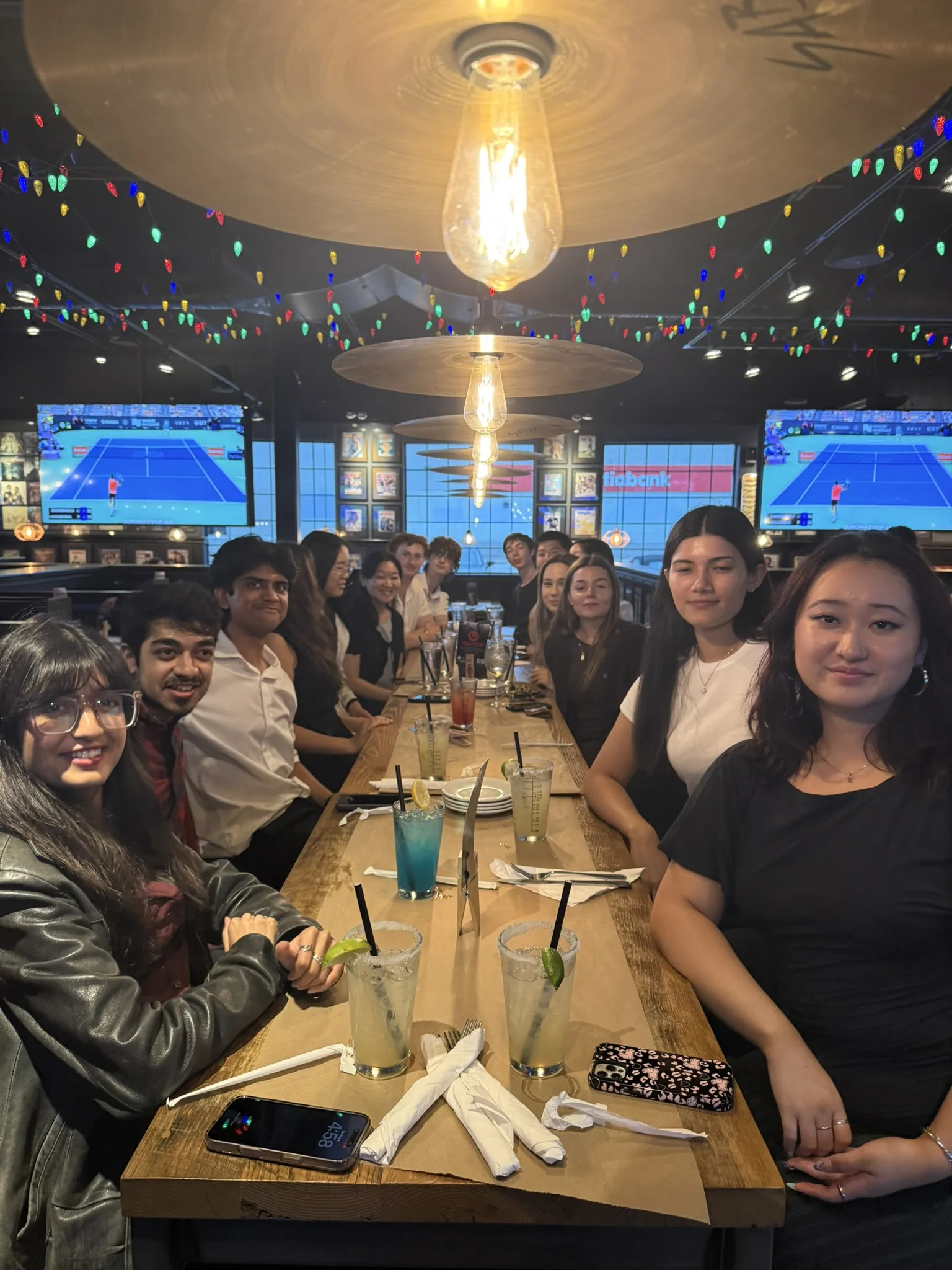 Team night out at a sports bar, 11 August 2026 — big group under the string lights.