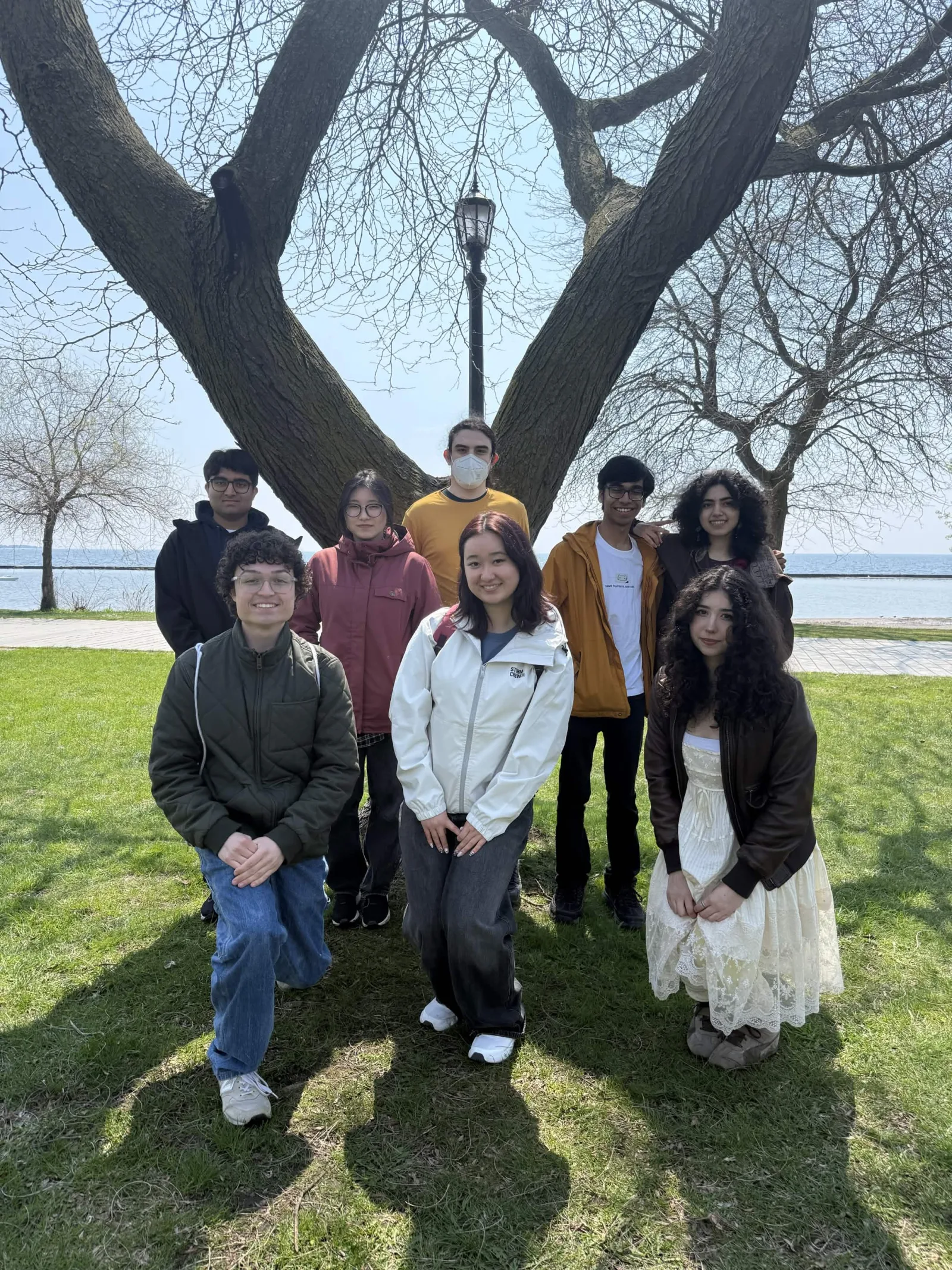 The team poses under a tree by the waterfront