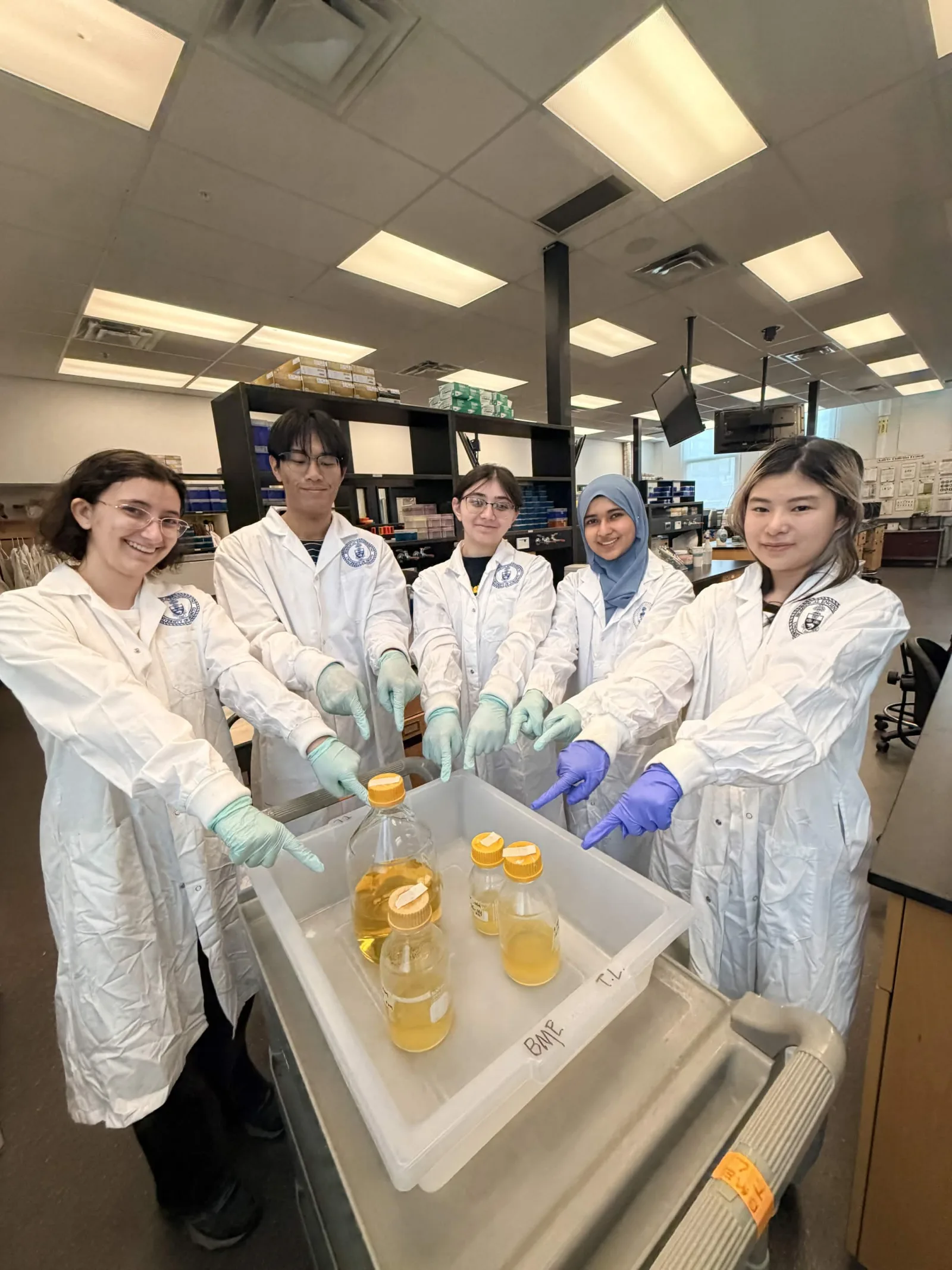 Wet-lab subgroup members in the teaching lab with culture bottles, June 2026